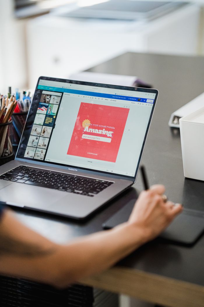 Personne utilisant un ordinateur portable et une tablette graphique pour un travail de conception numérique dans un bureau à domicile.